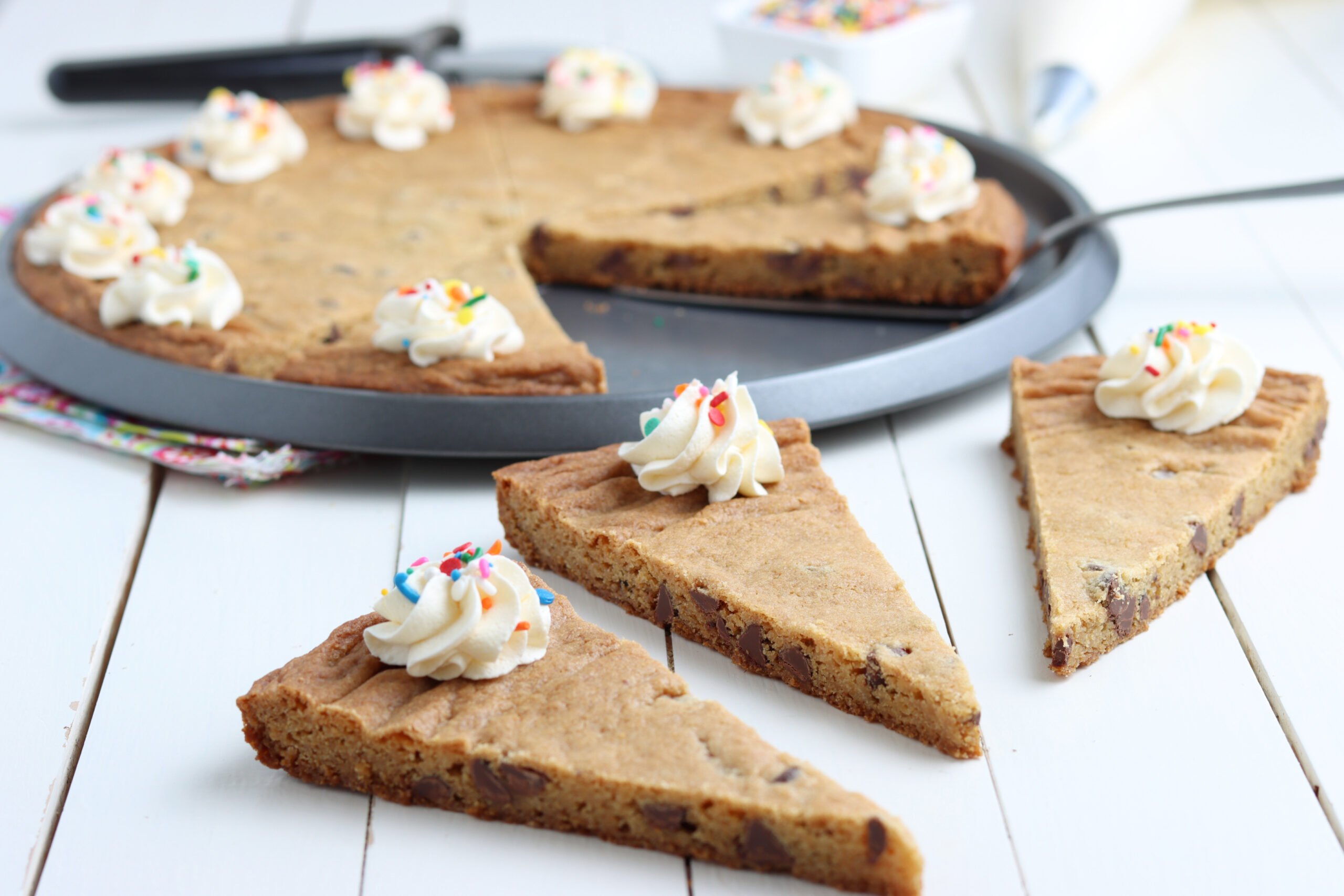 A chocolate chip pizza in the pan with three slices on the table 