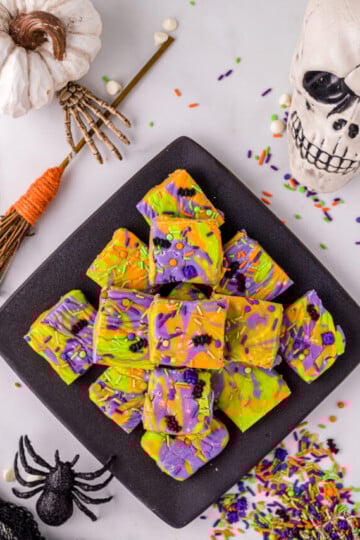 Hocus Pocus Fudge Bars in a black diamond plate with Halloween decorations surrounding it