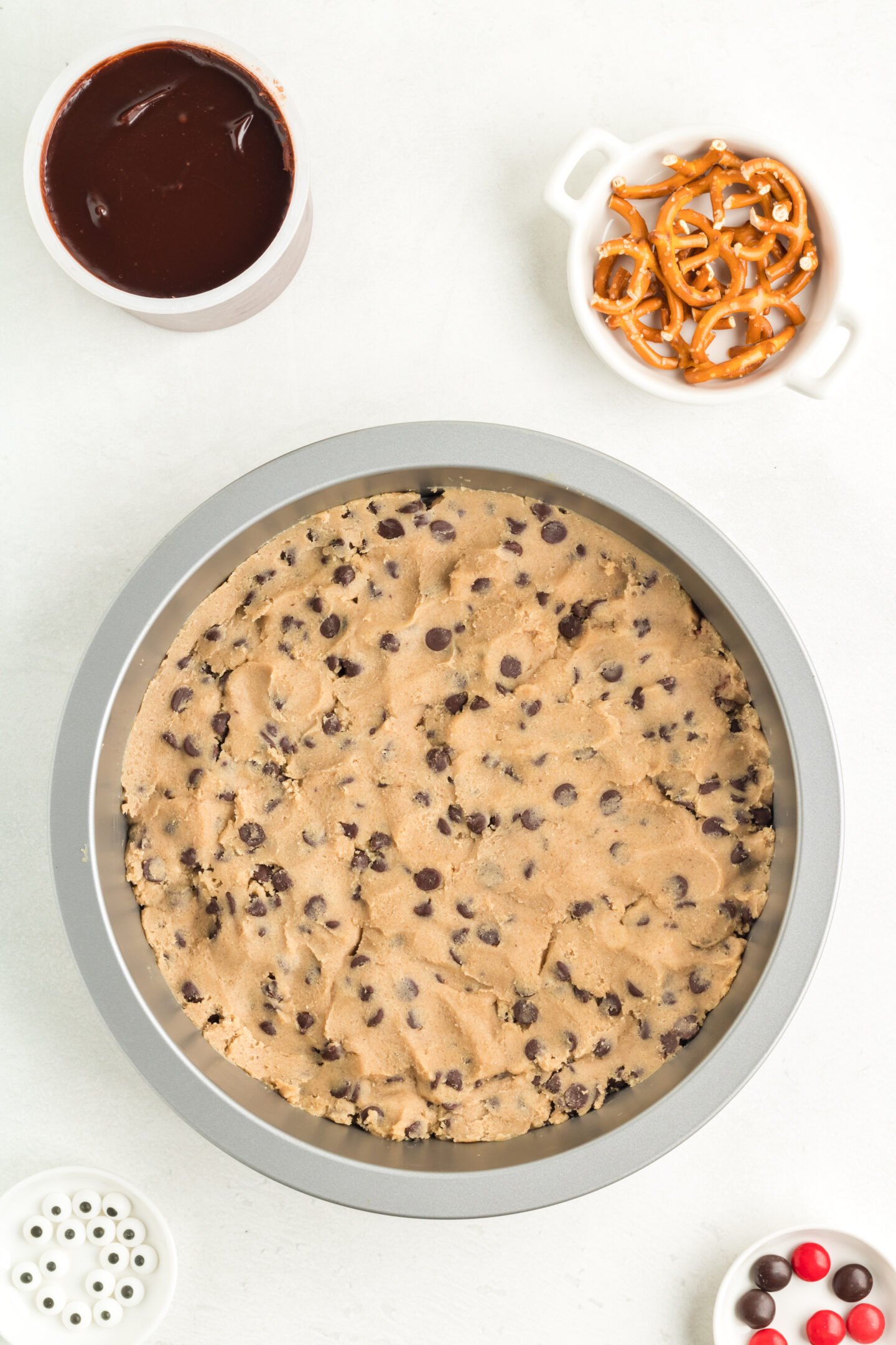 Raw cookie dough spread out in the bottom of a round pie plate. 