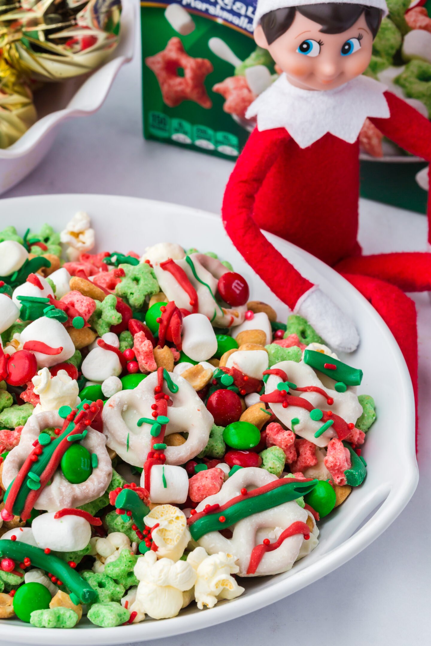 Elf on the Shelf sitting next to bowl of Mischief Munch Christmas snack mix