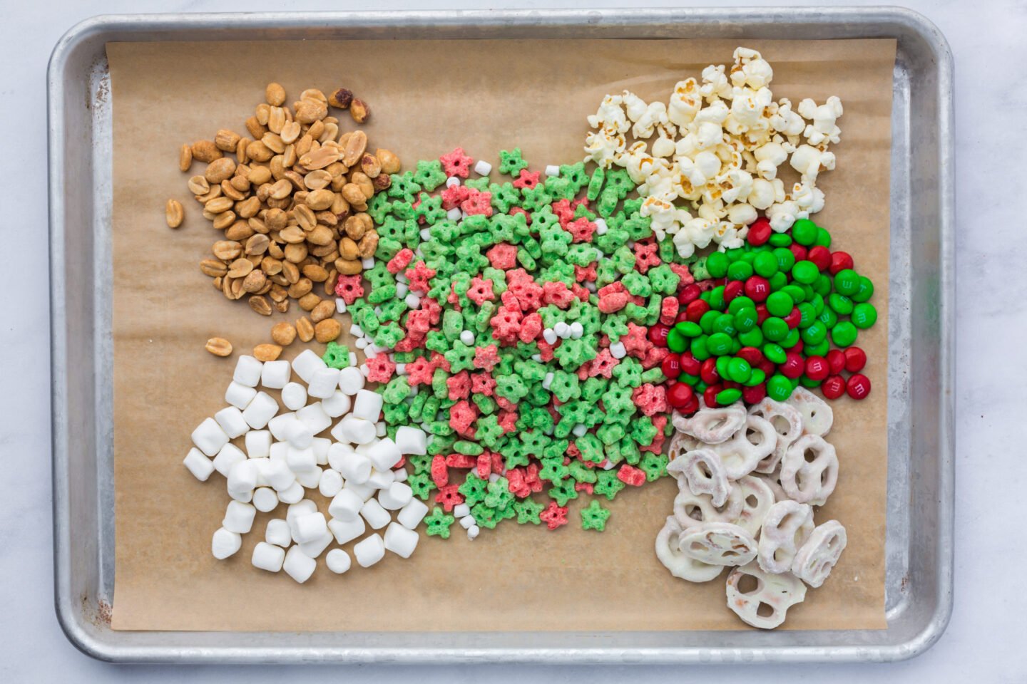Cereal, popcorn, pretzels, marshmallows, and M&Ms ready to be mixed for Christmas snack mix