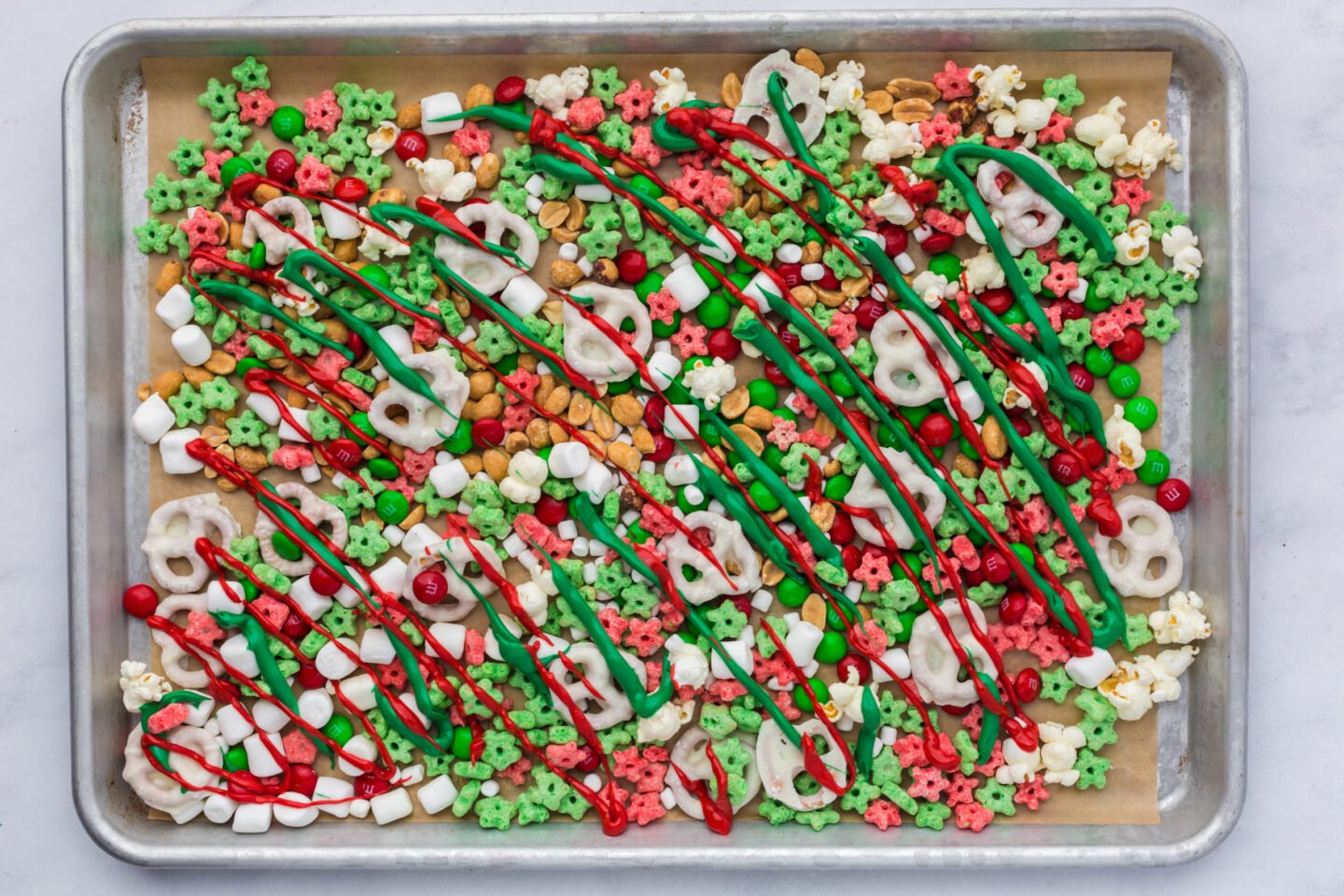 red and green melted candy over festive holiday snack mix before adding sprinkles