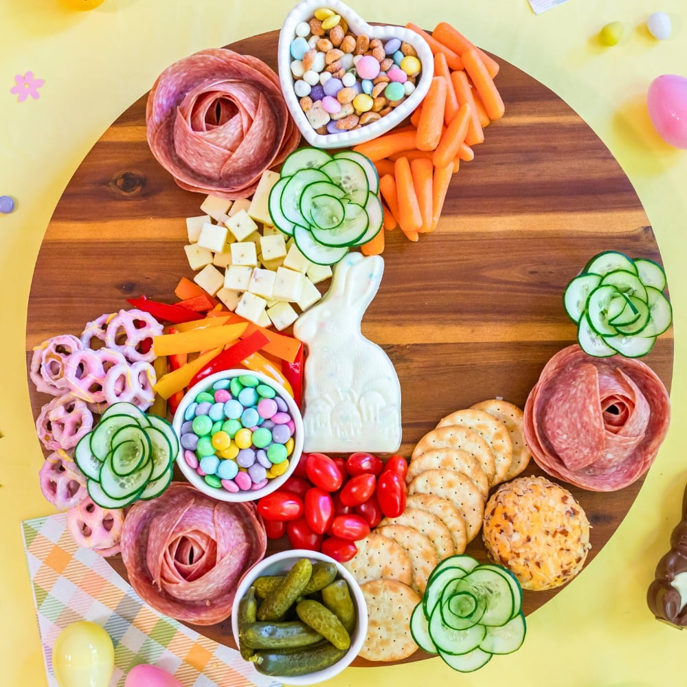 assembling Easter snack board step by step with cheese crackers and candy