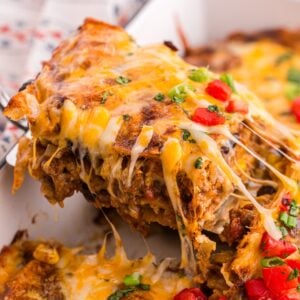 mexican casserole cheese pull with melted cheese stretching over layers of ground beef and tortillas