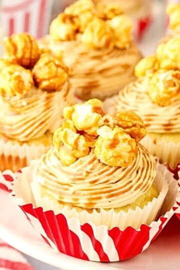 Caramel Popcorn Cupcakes arranged on a white platter, topped with buttery caramel popcorn and caramel drizzle