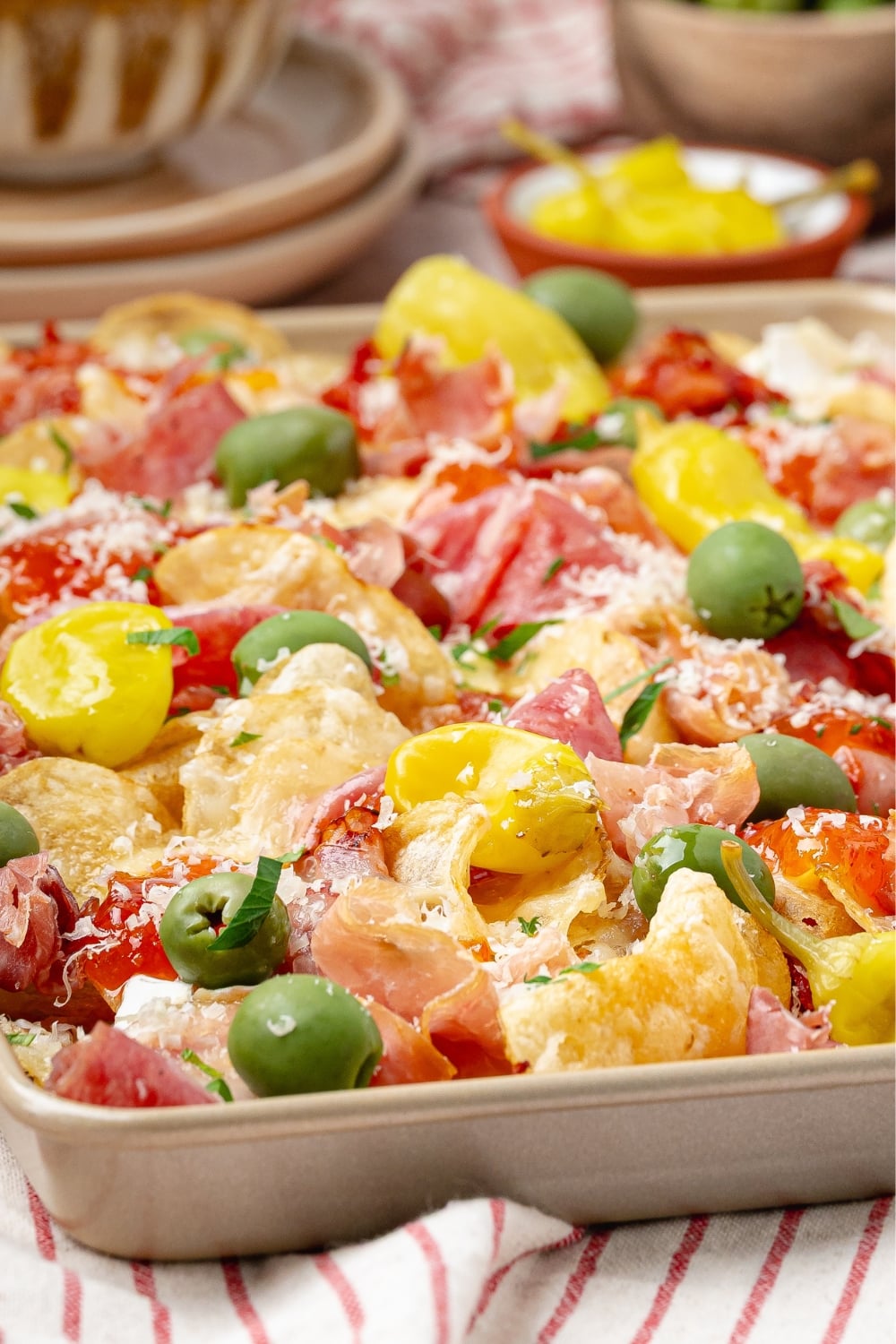 charcuterie nachos on a platter with melted brie prosciutto olives and hot honey drizzle