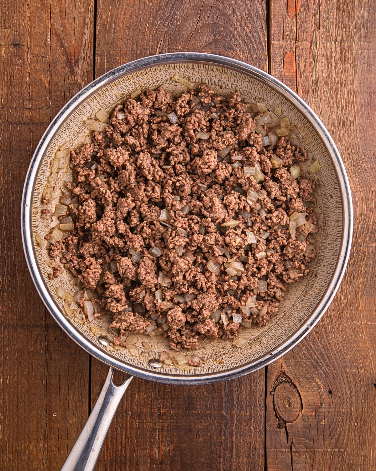 ground beef and diced onions cooking in skillet for Mexican casserole filling