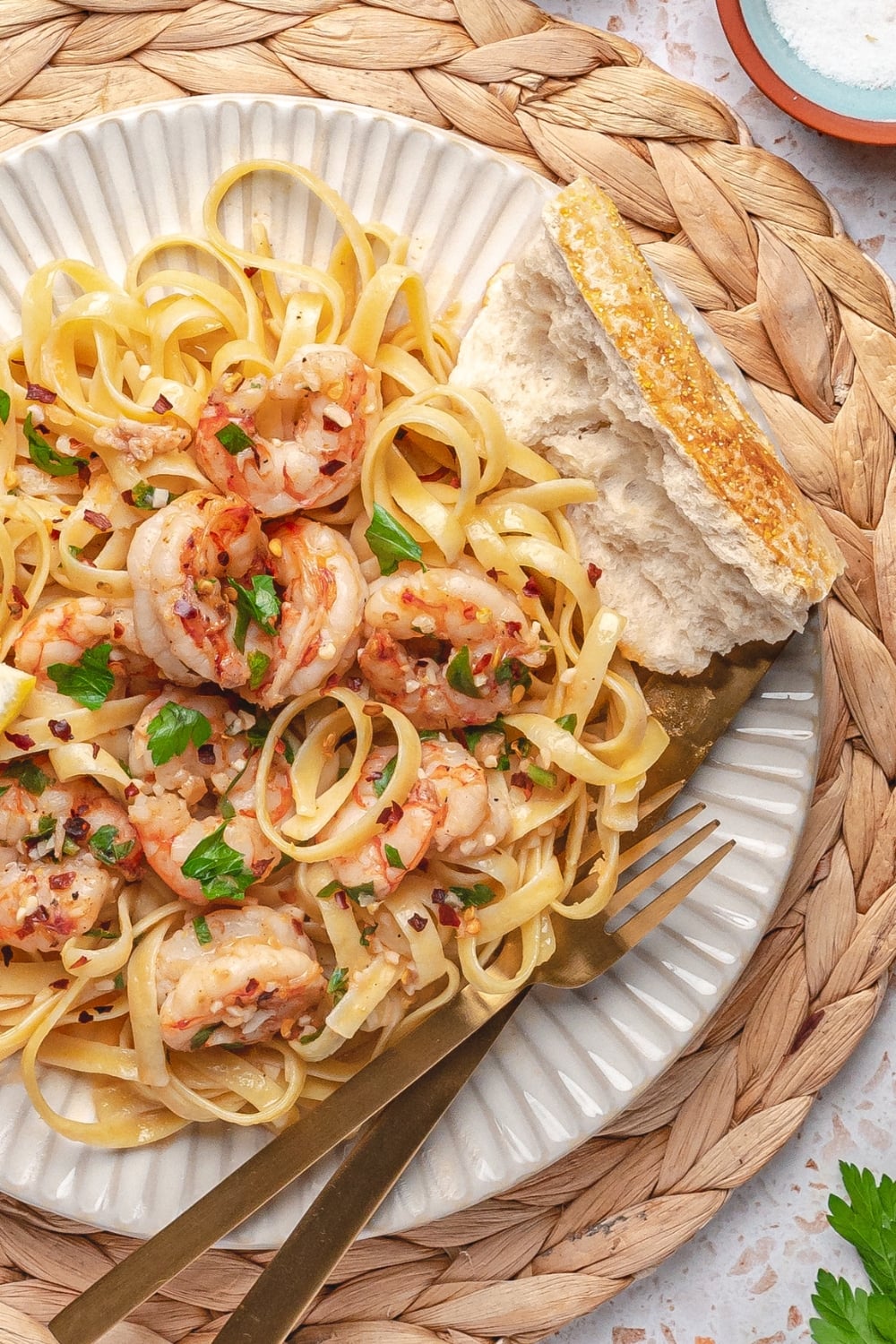 garlic butter shrimp served over pasta on white plate with fork on the side