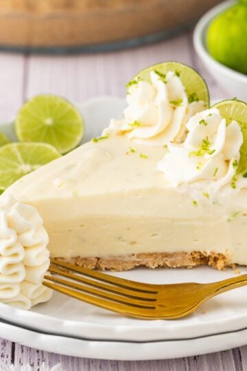 No-bake key lime pie with creamy lime filling, graham cracker crust, whipped cream topping, and fresh lime slices