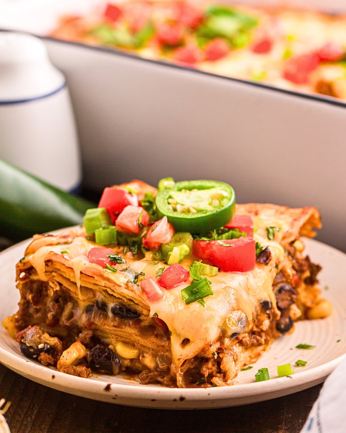 slice of mexican casserole served on plate with sour cream and toppings