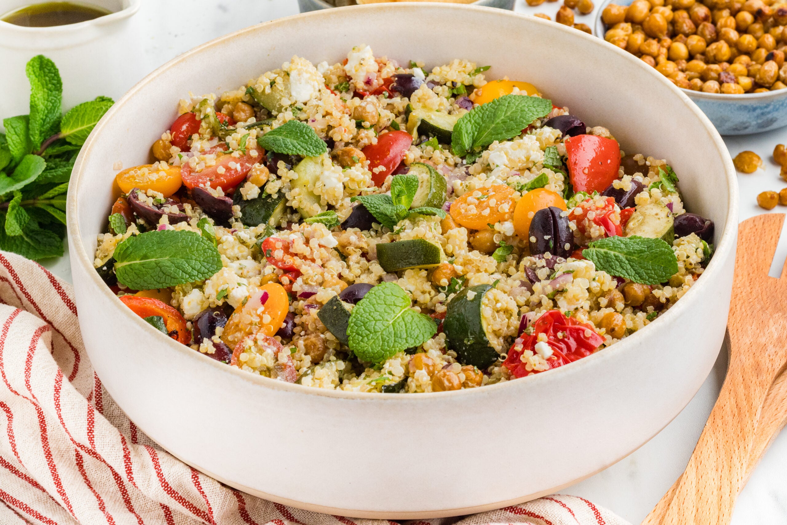 Greek quinoa salad with chickpeas, roasted vegetables, feta cheese, Kalamata olives, and lemon dressing in a serving bowl.