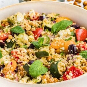 Healthy Greek Quinoa Salad with roasted vegetables, chickpeas, feta cheese, olives, tomatoes, and fresh herbs in a large serving bowl.