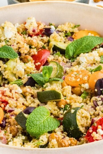 Healthy Greek Quinoa Salad with roasted vegetables, chickpeas, feta cheese, olives, tomatoes, and fresh herbs in a large serving bowl.