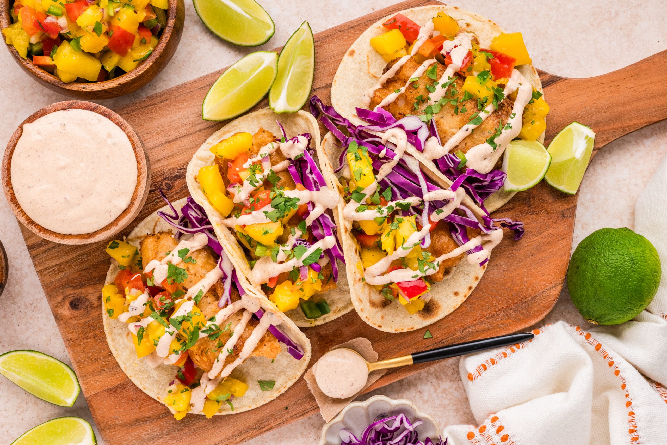 Crispy beer battered cod tacos topped with fresh mango salsa, purple cabbage, and creamy chipotle sauce.