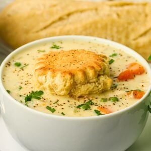 Creamy Chicken Pot Pie Soup with shredded chicken, carrots, celery and peas served in a bowl with a warm buttermilk biscuit