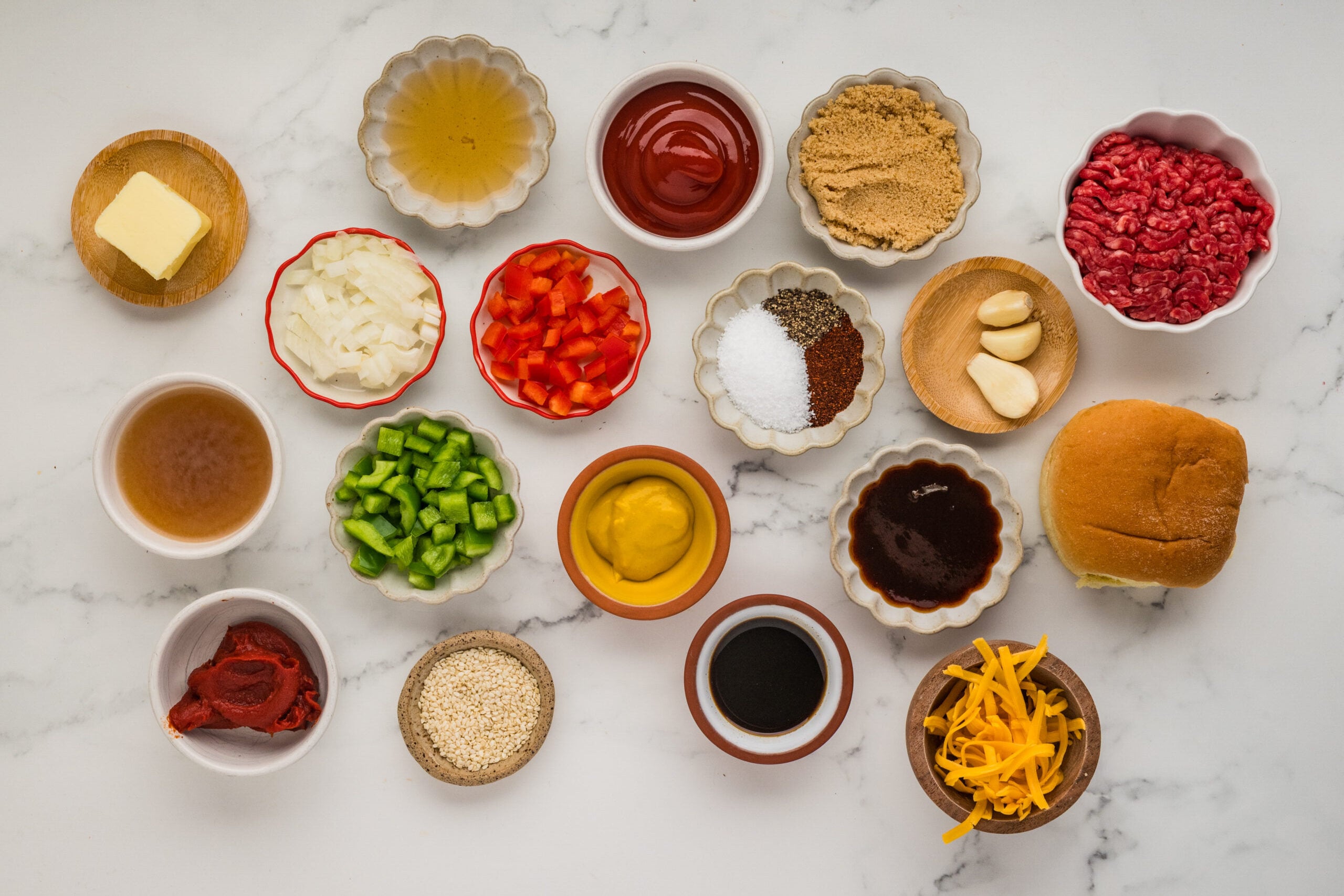 Ingredients for Sloppy Joe casserole including ground beef, peppers, ketchup, BBQ sauce, cheddar cheese and slider buns
