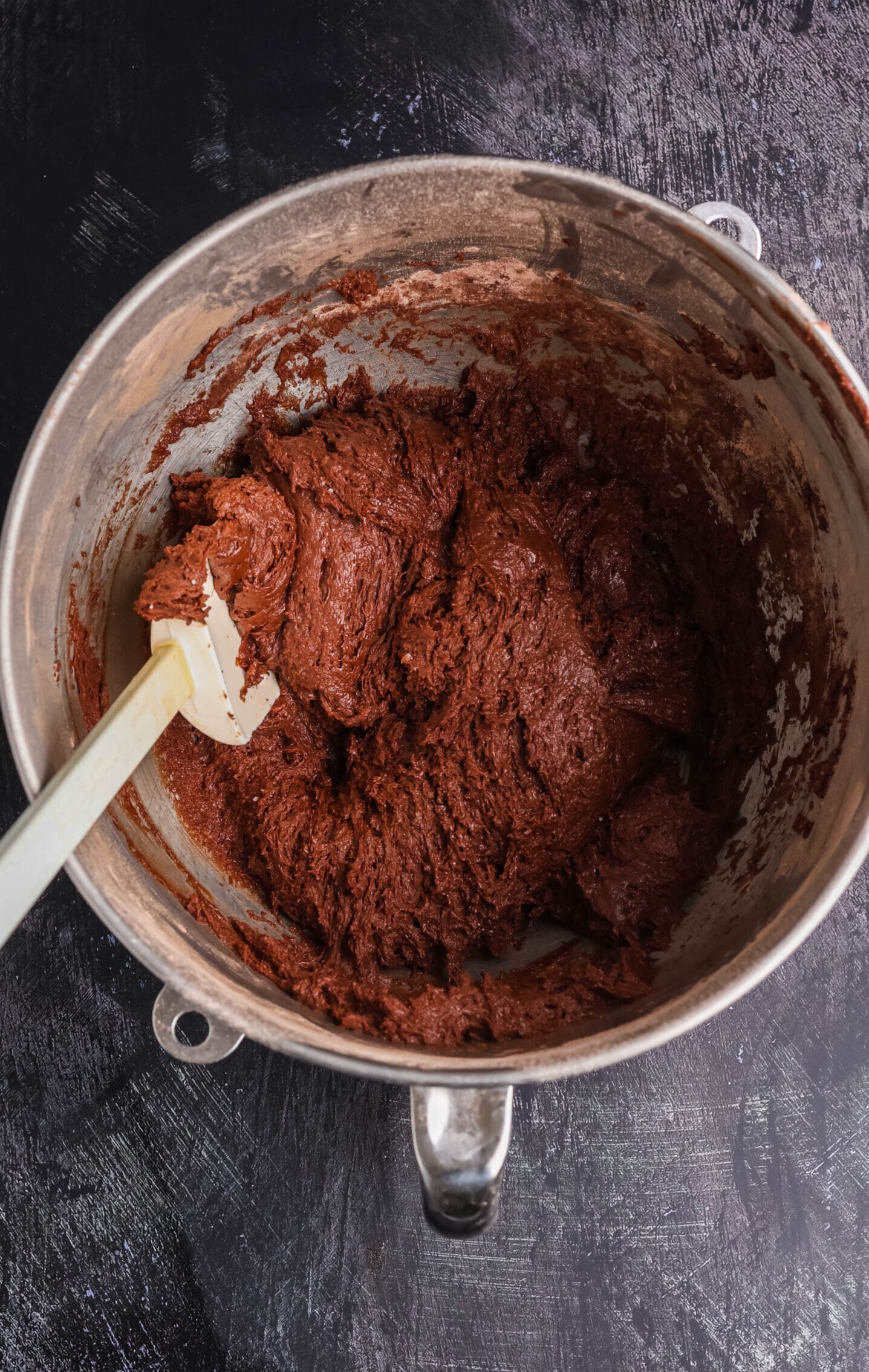 Thick chocolate cupcake batter with chocolate chips in a mixing bowl